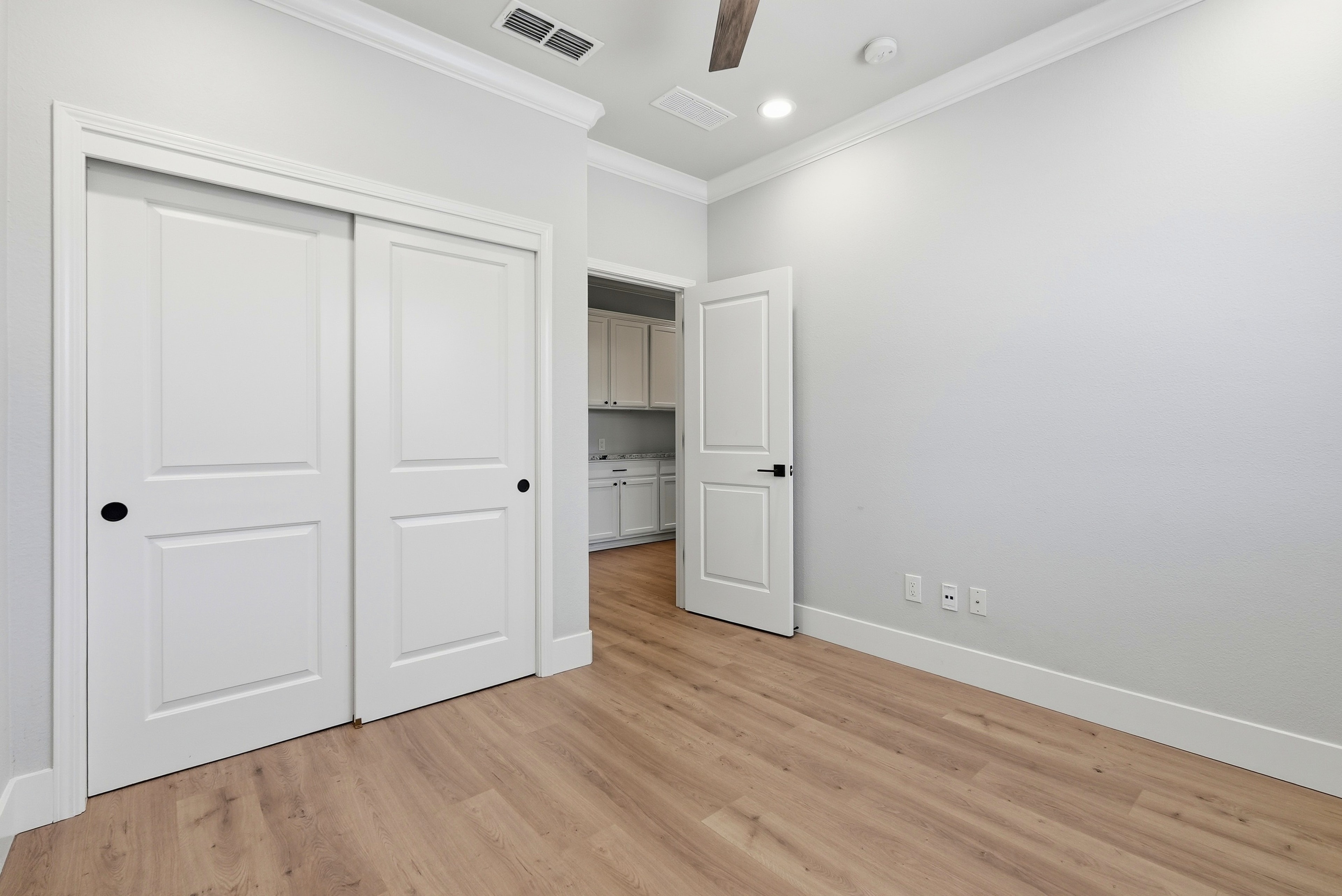 Bright bedroom with sliding closet doors, wood flooring and ceiling fan