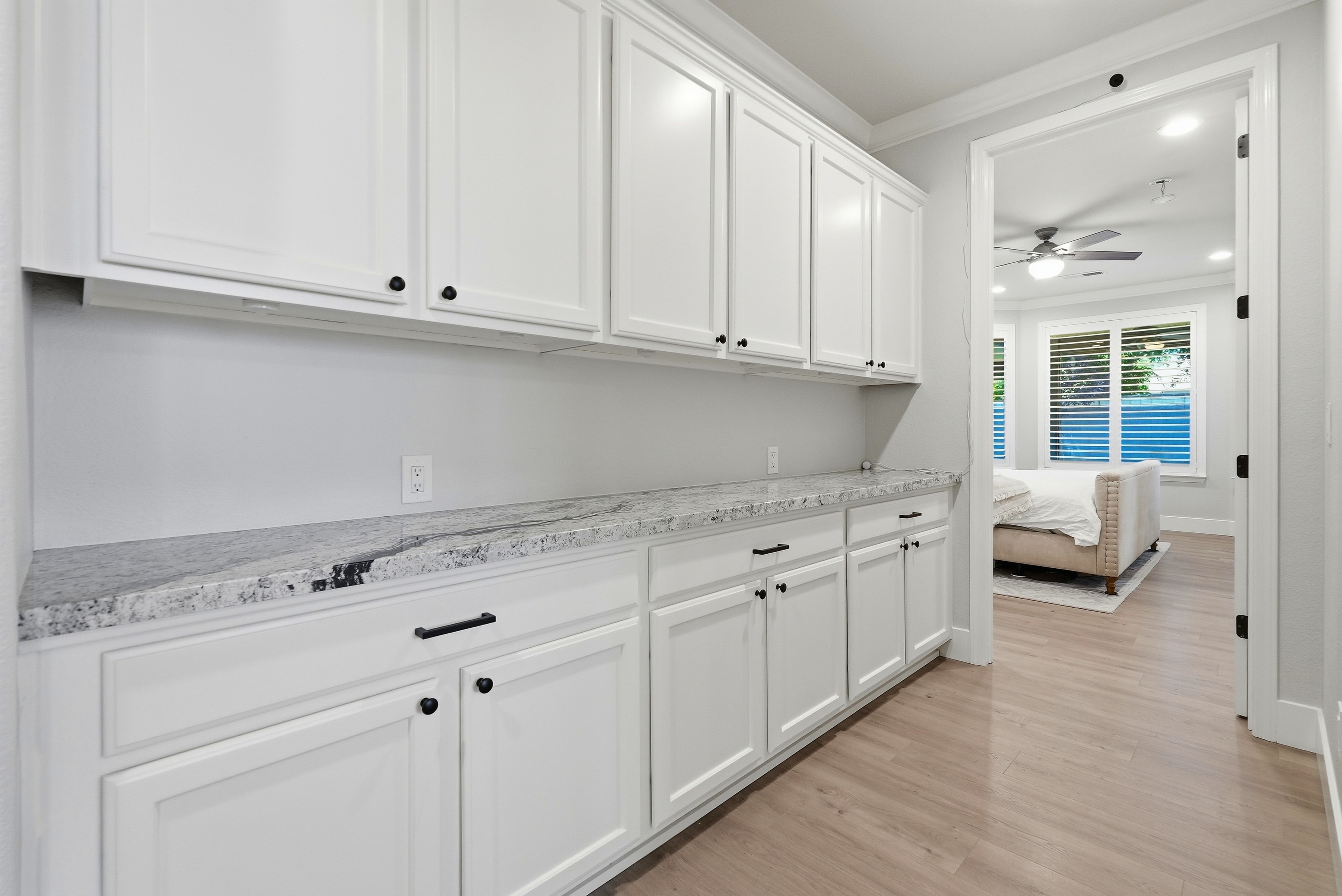 Hallway with white cabinetry, granite countertops and view into bedroom