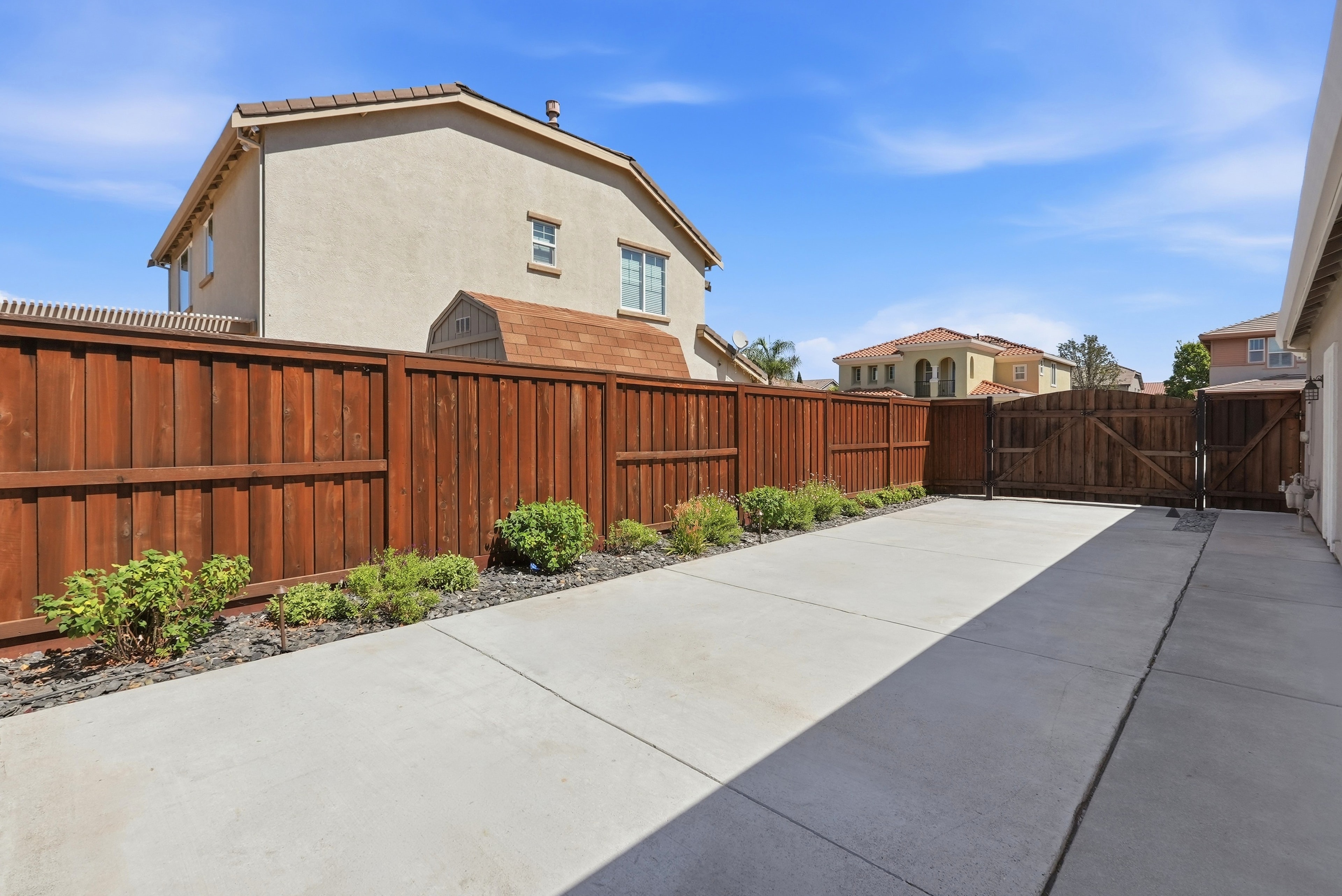 Wide concrete side yard with wood fence gate — RV, boat, and toy hauler access